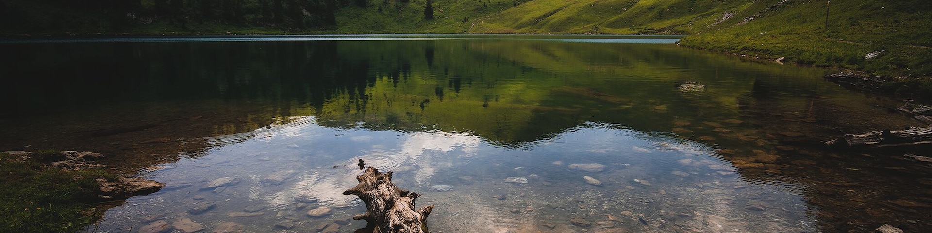 One of the mountain lakes in Stockhorn, beautiful and calm during the sunny day, two wooden benches are on site to provide the hikers a place to rest and eat their picnic.