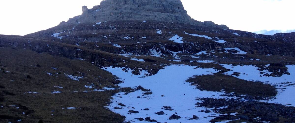 A mountain with a snow-covered peak and surrounding rocky terrain.