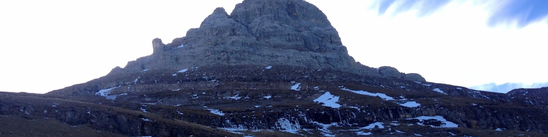 A mountain with a snow-covered peak and surrounding rocky terrain.