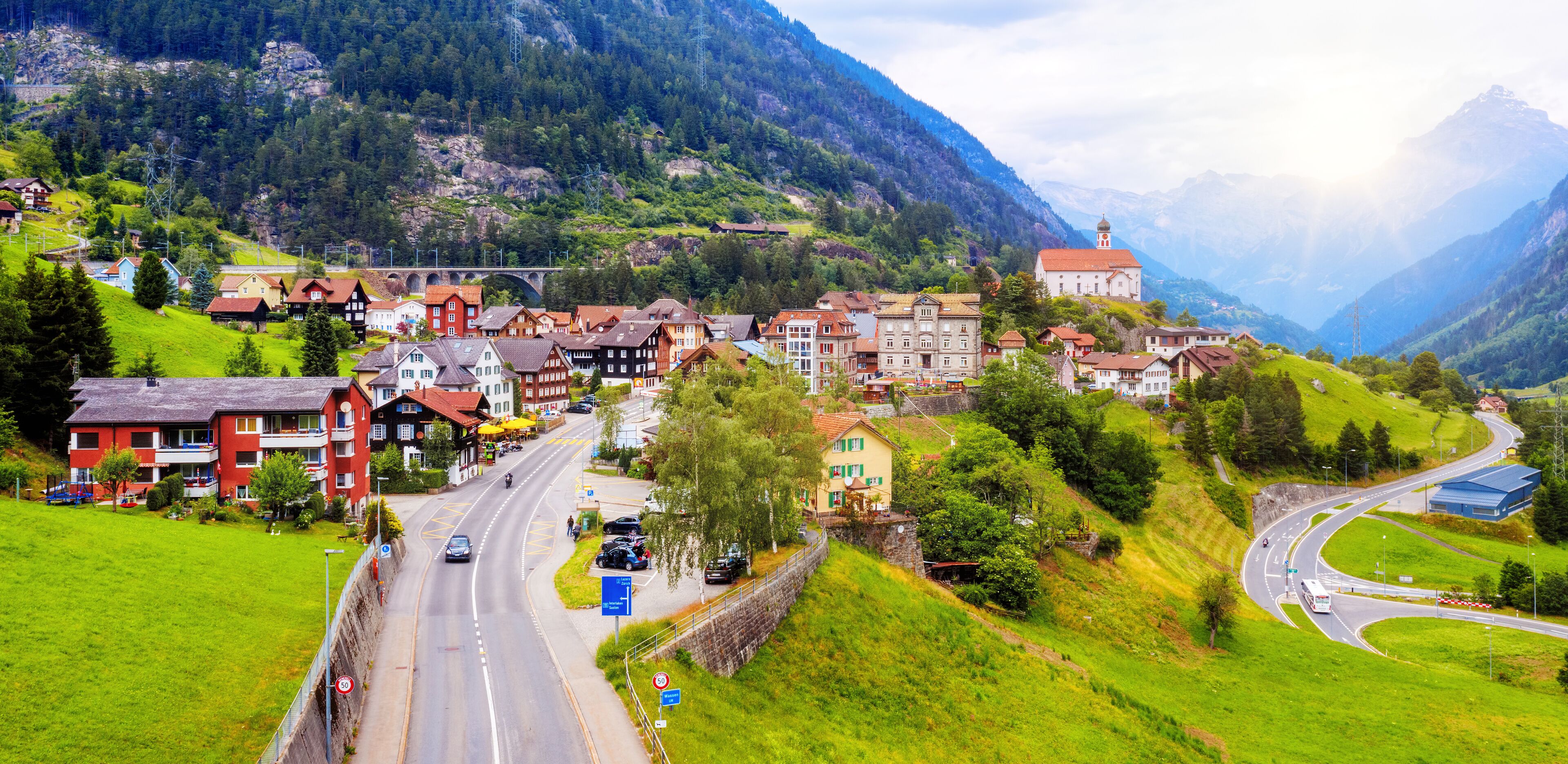 A mountainous town with a winding road, historic buildings, and a church.