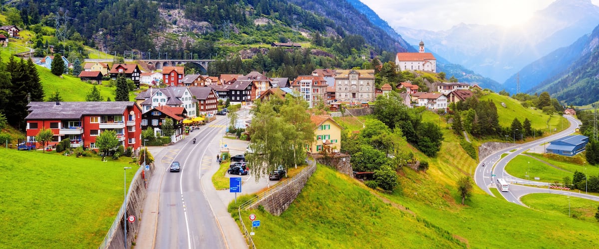 A mountainous town with a winding road, historic buildings, and a church.