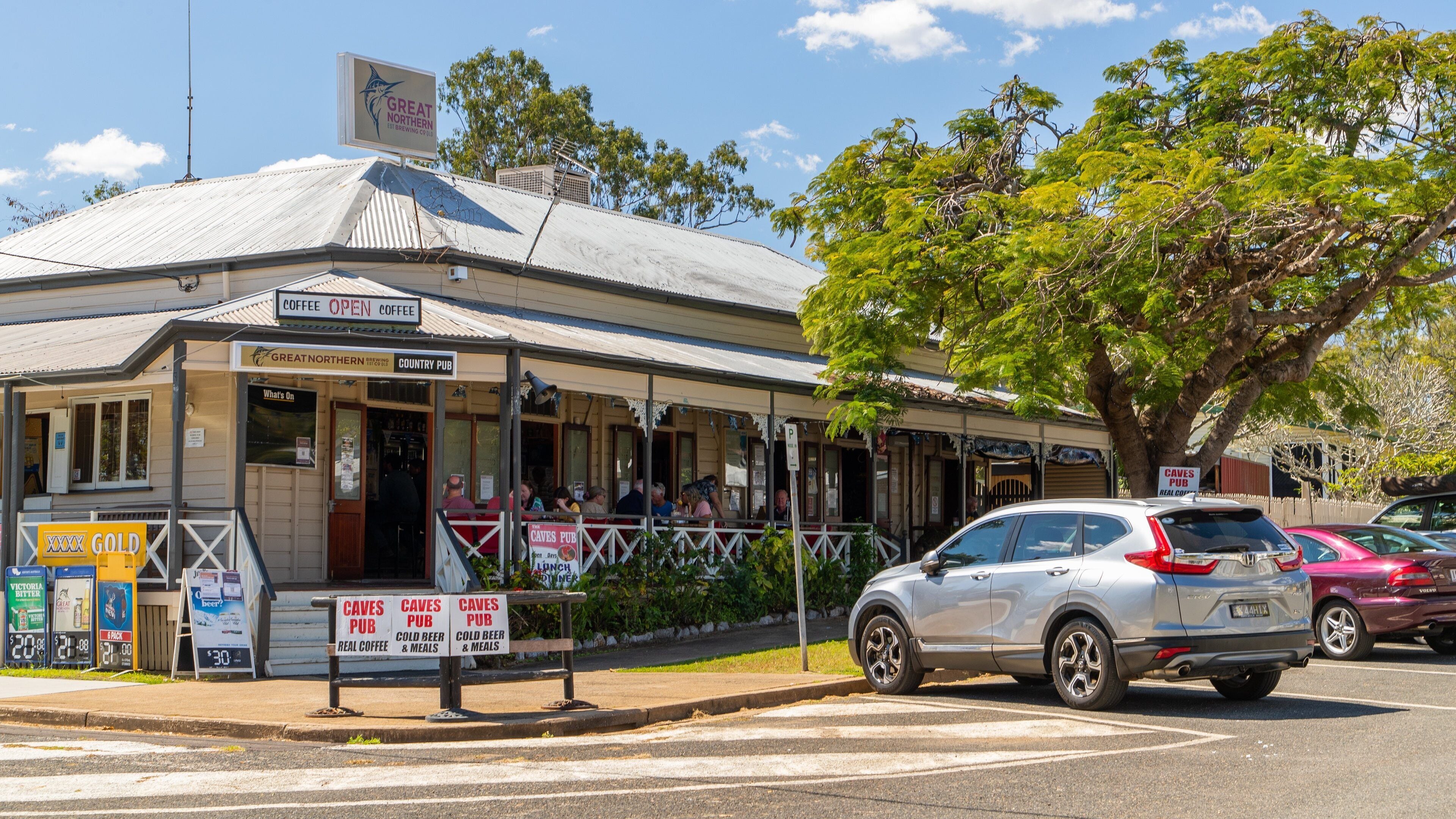 A country pub with outdoor seating, a sign for Great Northern Brewing Co., and a parked car.