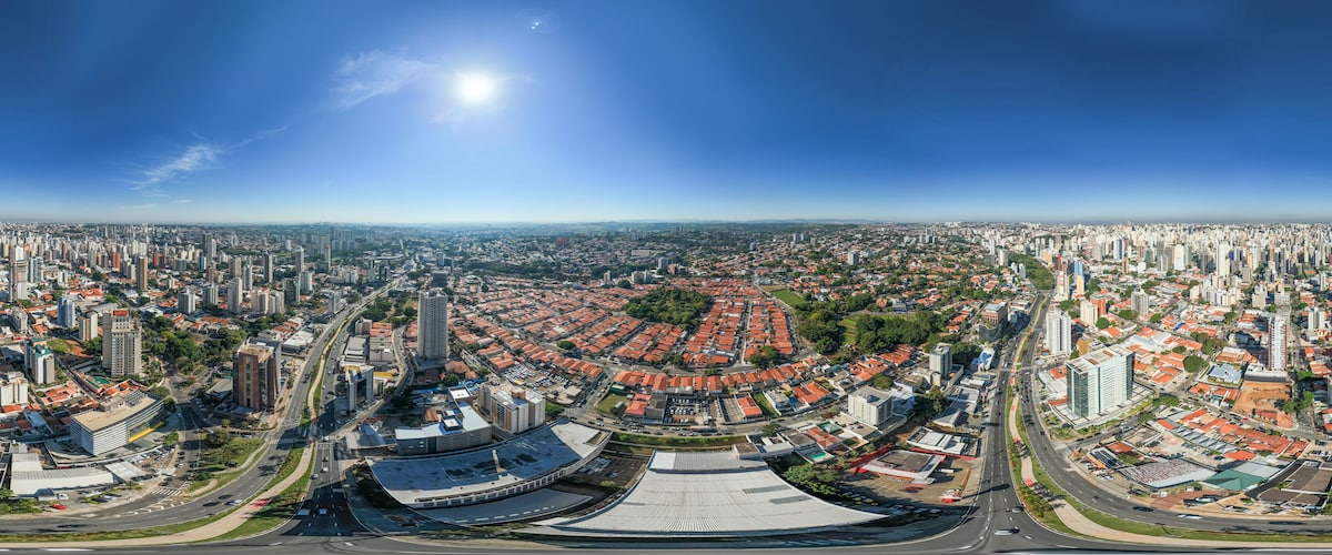 A panoramic cityscape with a prominent stadium, dense urban buildings, and a clear blue sky.