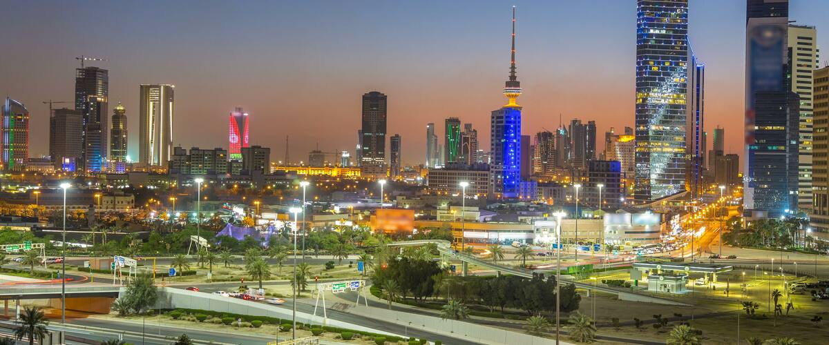 A city skyline at dusk with illuminated buildings and a prominent tower.