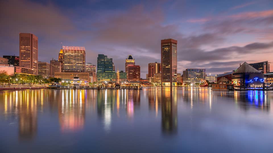 Baltimore, Maryland, USA. Cityscape image of downtown Baltimore, Maryland with reflection of the skyline in the water at beautiful autumn sunrise.
