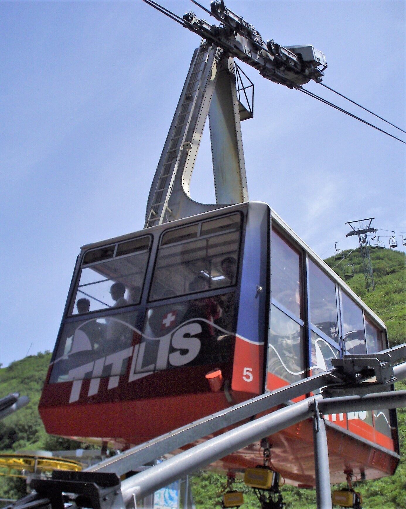 View of a cable car descending the mountain behind us. 
As you descend Mt Titlis the scenery changes to cows grazing in green meadows and scenic lakes from the snowclad mountains above. There are around 200 cable cars operating to and from the mountain, each sporting different national flags.  #mountains

