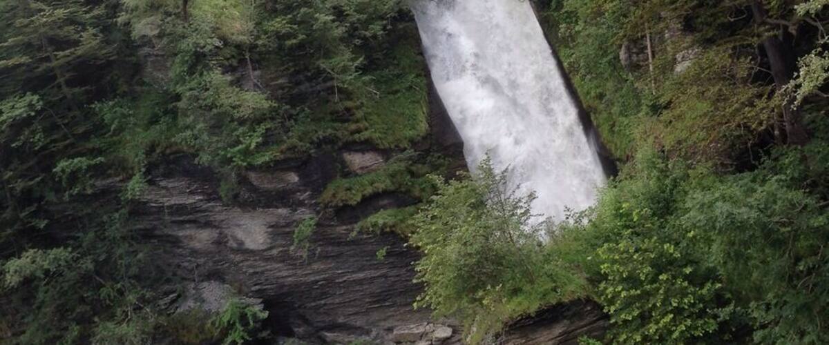 A waterfall cascading down a rocky cliff surrounded by dense forest.