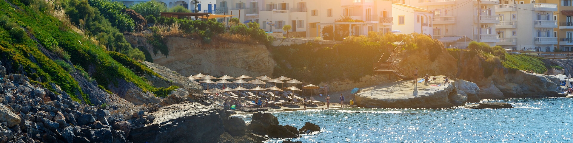 A coastal town with buildings, rocky shoreline, and clear blue sea.