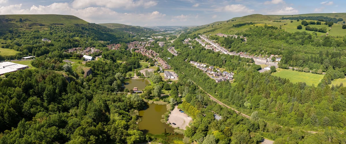 A valley with a river, surrounded by dense forests and rolling hills.