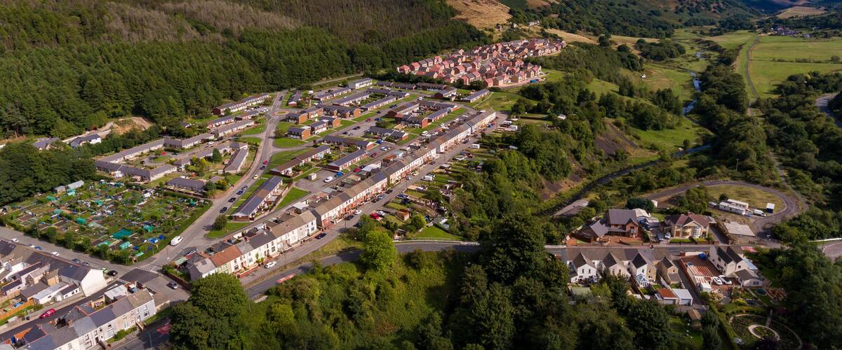 An aerial view of a residential area with houses, roads, and surrounding greenery.