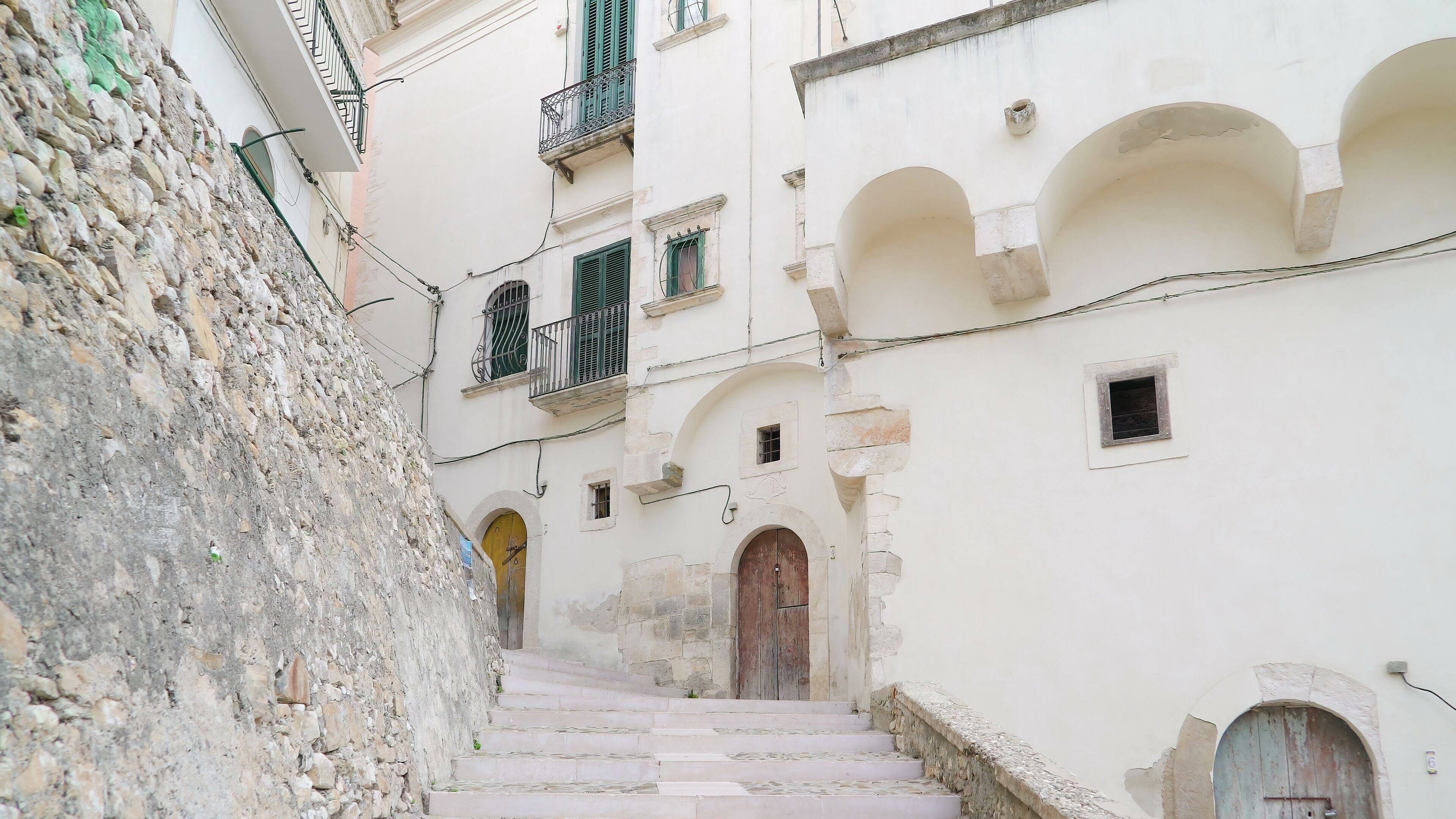A narrow street flanked by historic buildings with stone walls and arched doorways.