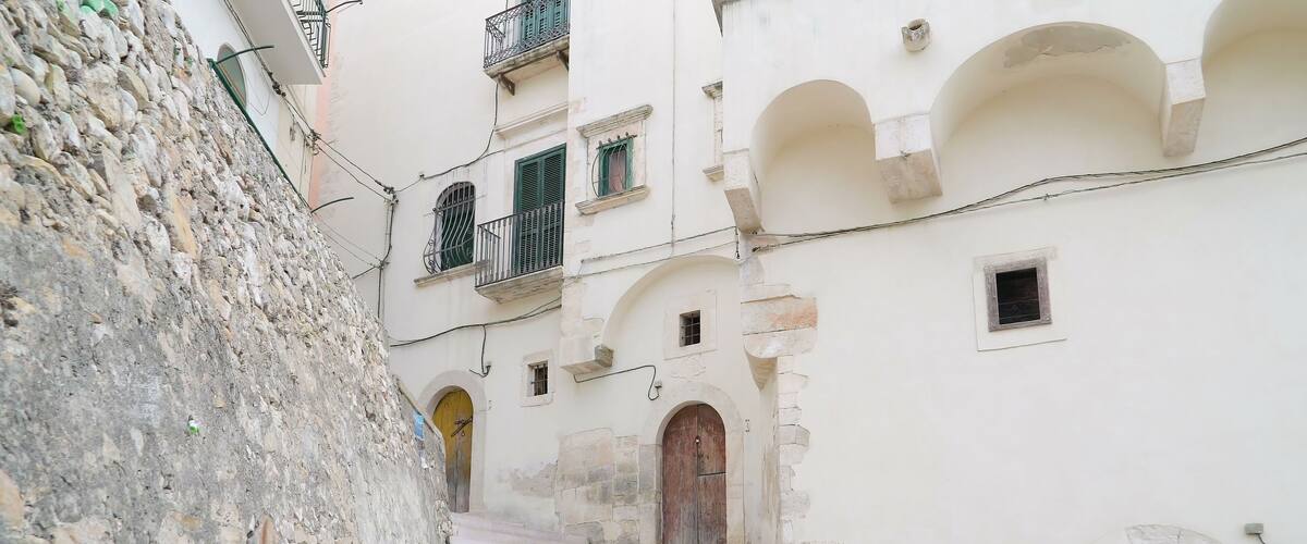 A narrow street flanked by historic buildings with stone walls and arched doorways.