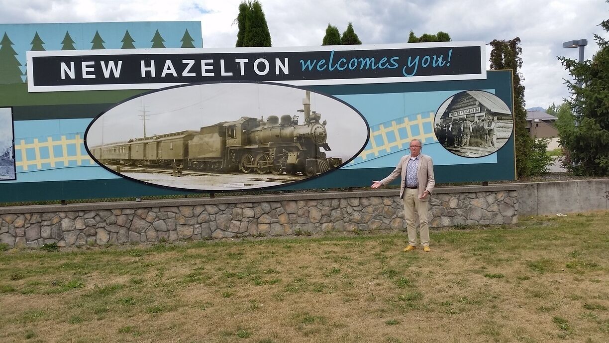 A welcome sign for New Hazelton with a vintage train and a historical photo.