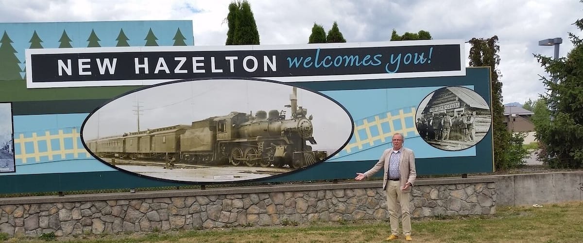A welcome sign for New Hazelton with a vintage train and a historical photo.