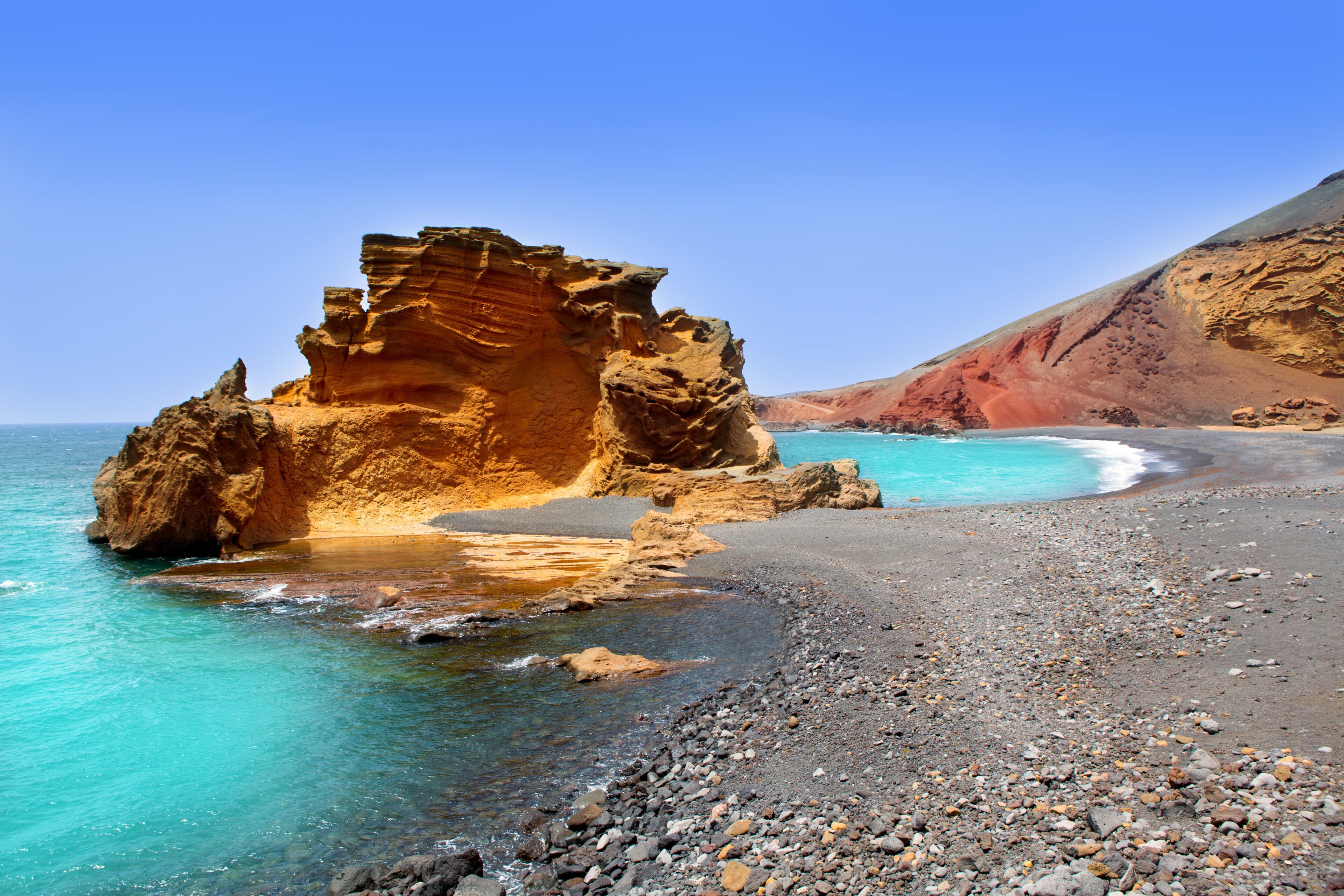 A rocky coastline with clear turquoise waters and a prominent rock formation.