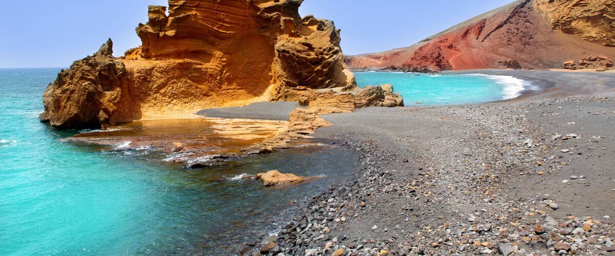 A rocky coastline with clear turquoise waters and a prominent rock formation.