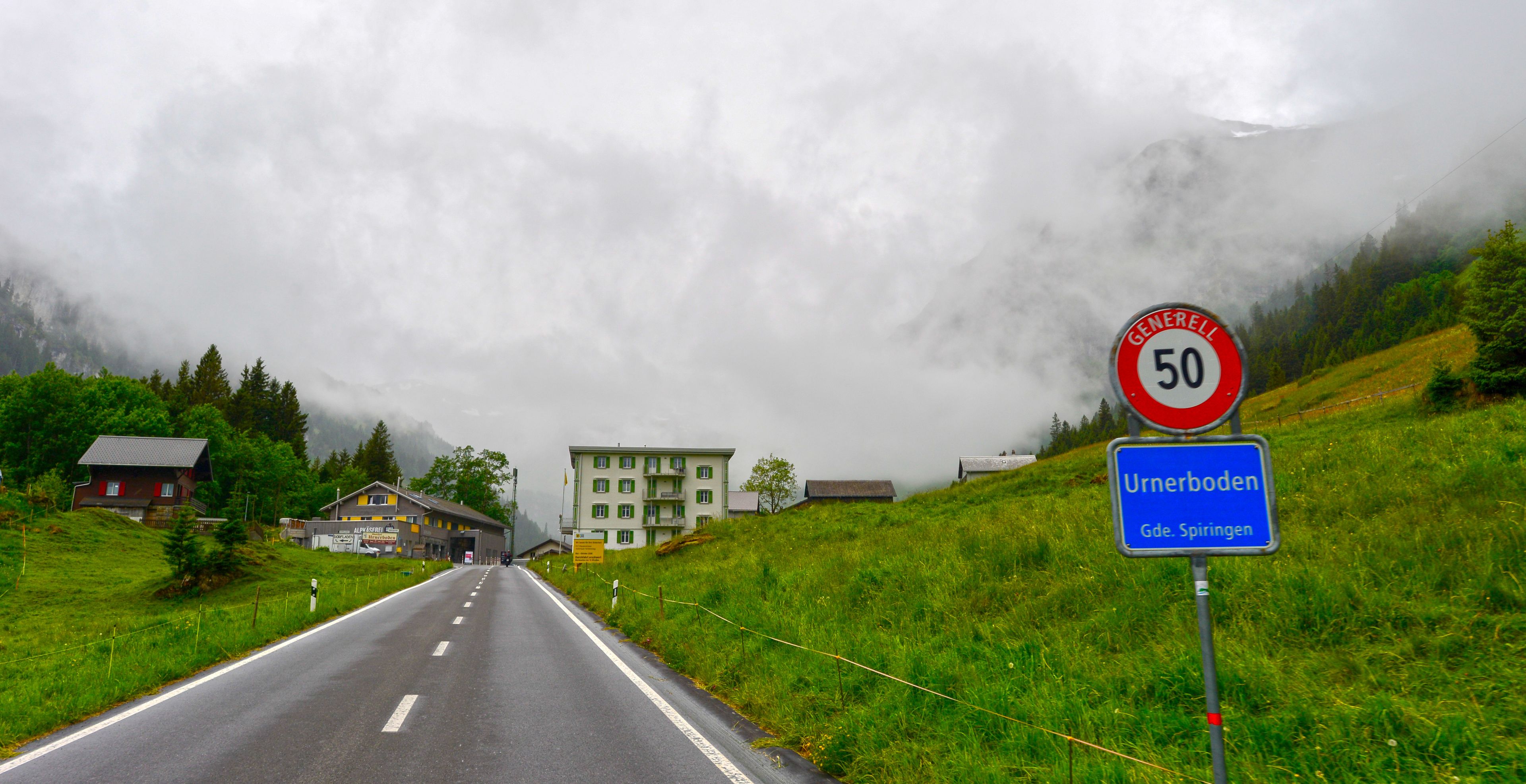 Einfahrt auf der Klausenpassstrasse nach Urnerboden mit Blick auf das Ortsschild vor Nebelbergen, Kanton Uri, Schweiz