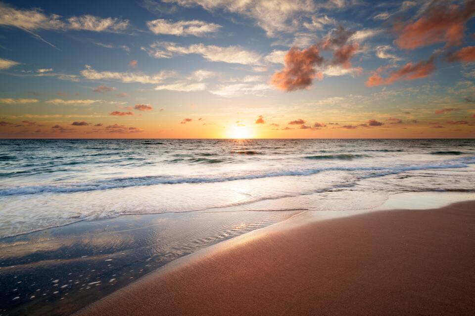 Una playa con olas al atardecer.