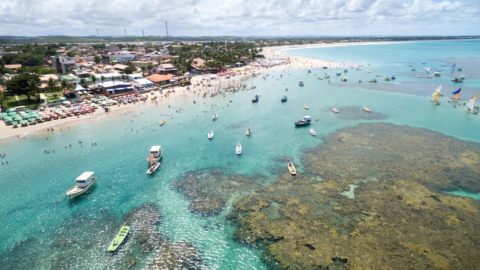 Un pueblo costero con playa, barcos y aguas turquesas cristalinas.