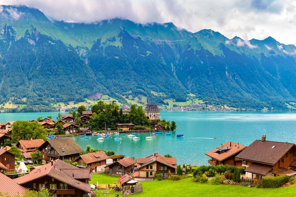 A lakeside village with traditional houses, boats, and a mountain backdrop.
