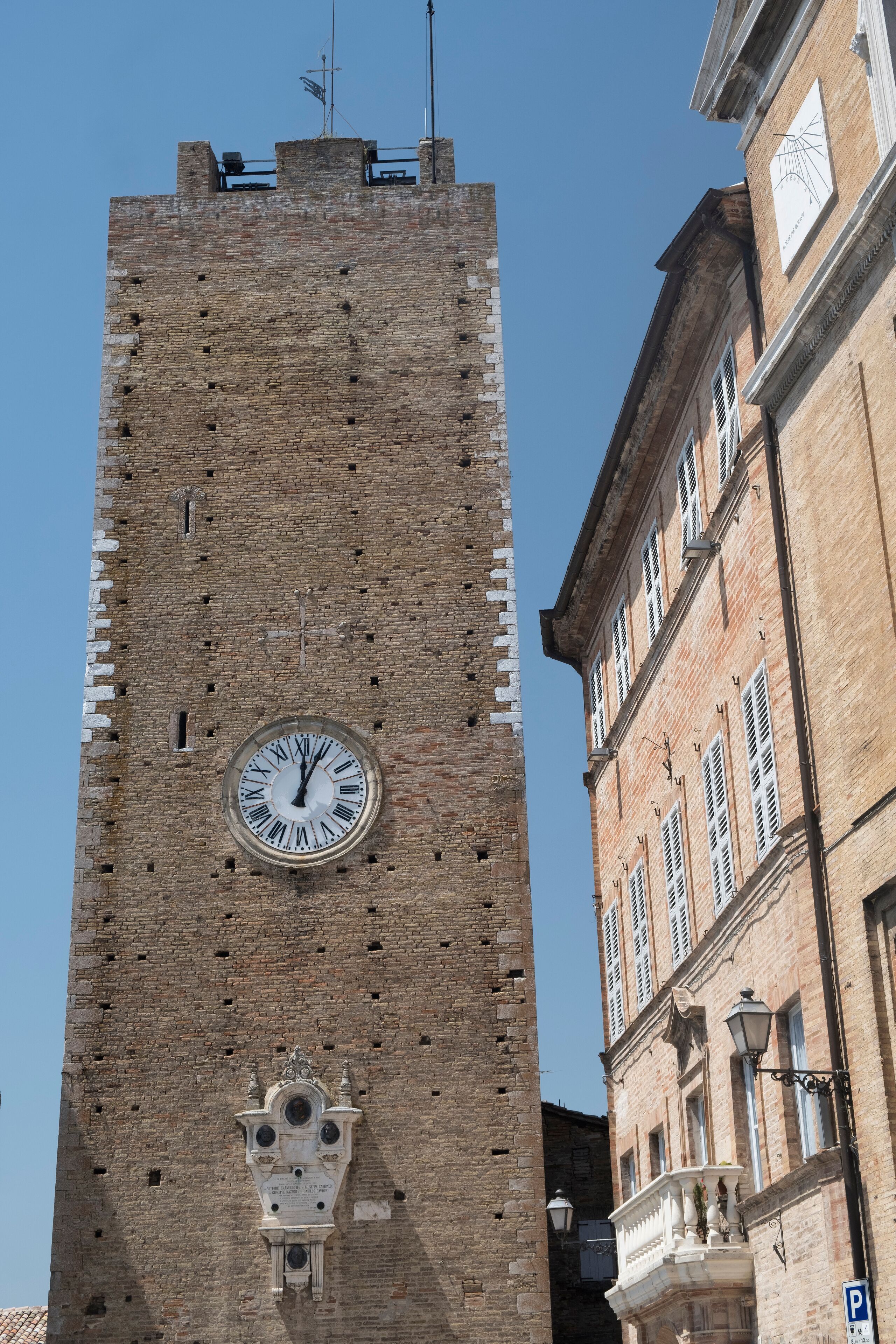A tall brick tower with a clock and a weather vane.