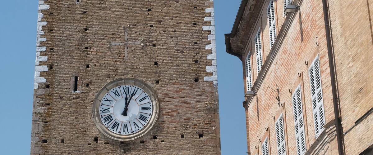 A tall brick tower with a clock and a weather vane.