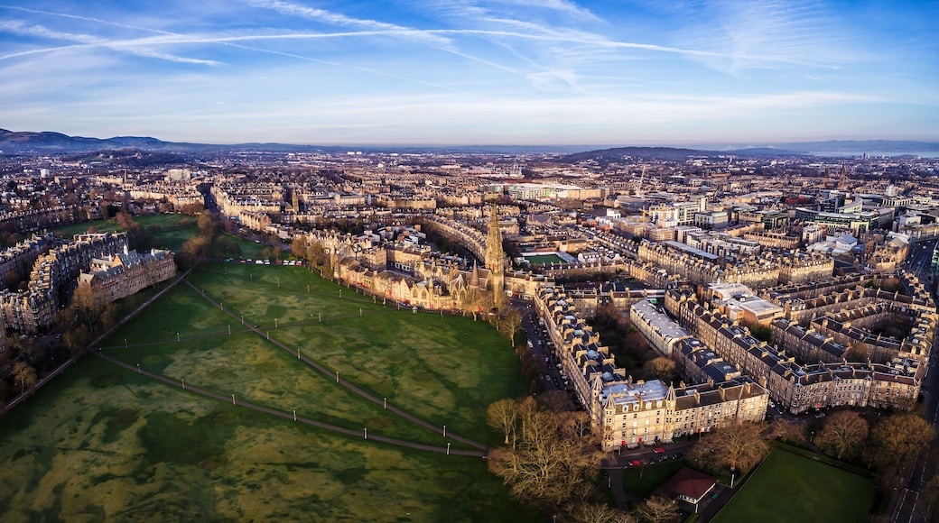 An aerial view of a city with historic architecture, a large green park, and a river.