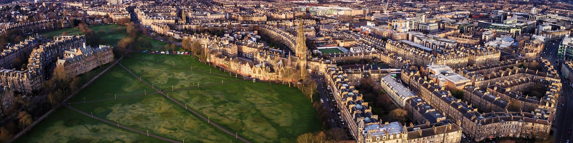 An aerial view of a city with historic architecture, a large green park, and a river.