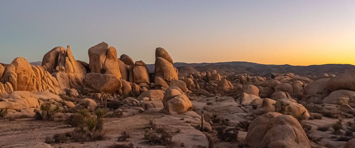 A desert landscape with prominent rock formations and sparse vegetation.