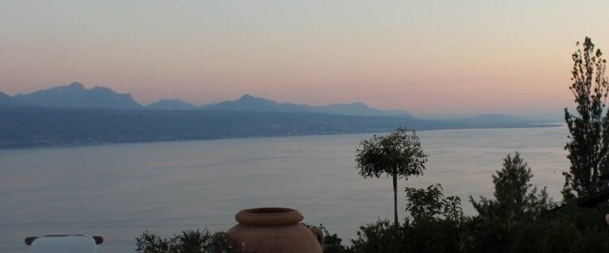 A patio with outdoor furniture overlooking a body of water and mountains in the distance.