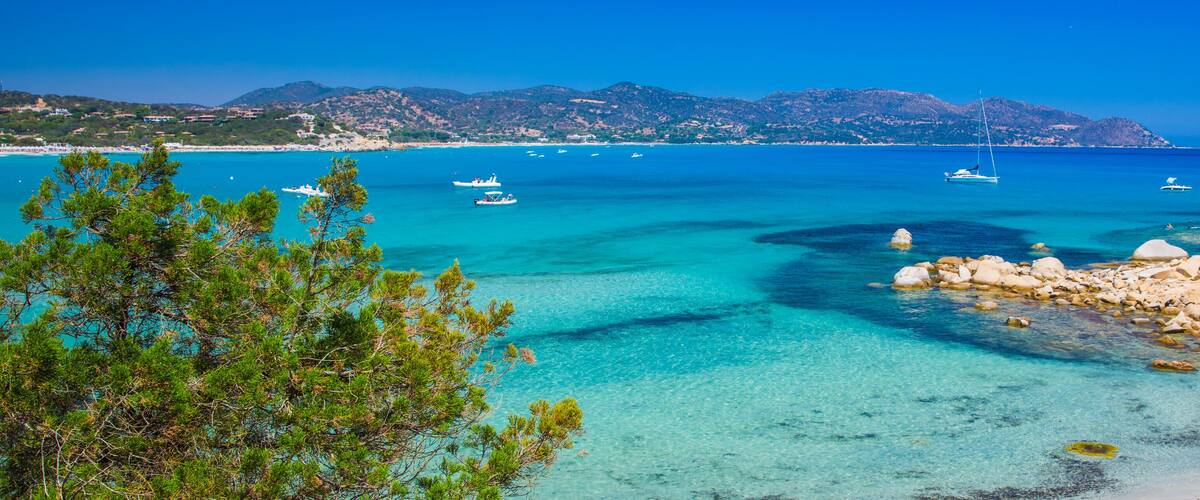 A coastal landscape with clear turquoise waters, rocky shorelines, and boats.