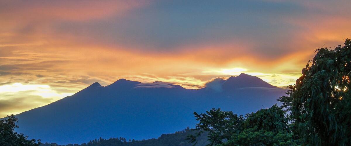 A mountain range at sunset with clouds and trees.