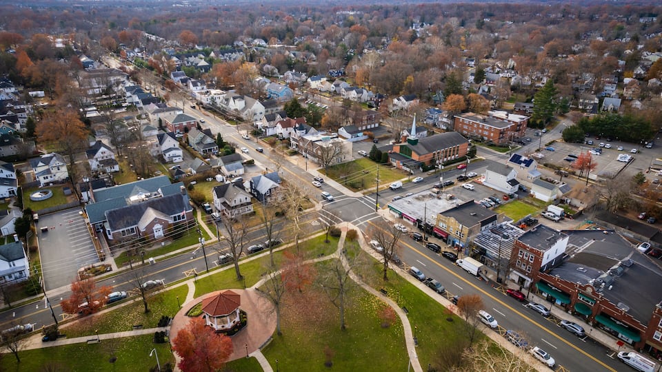 An aerial view of a town with a central roundabout, residential areas, and commercial buildings.