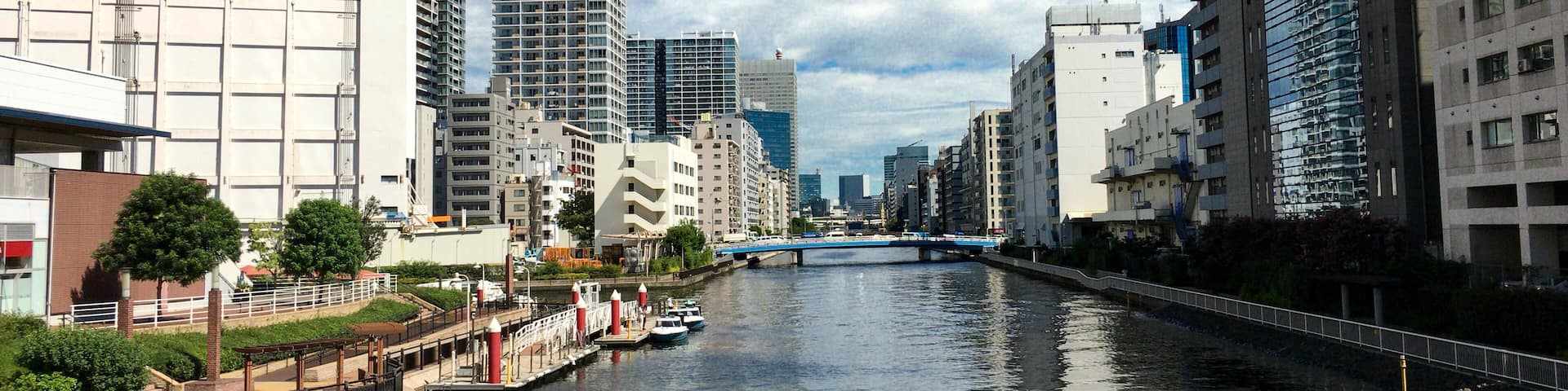 A river with a bridge, modern buildings, and a clear blue sky.