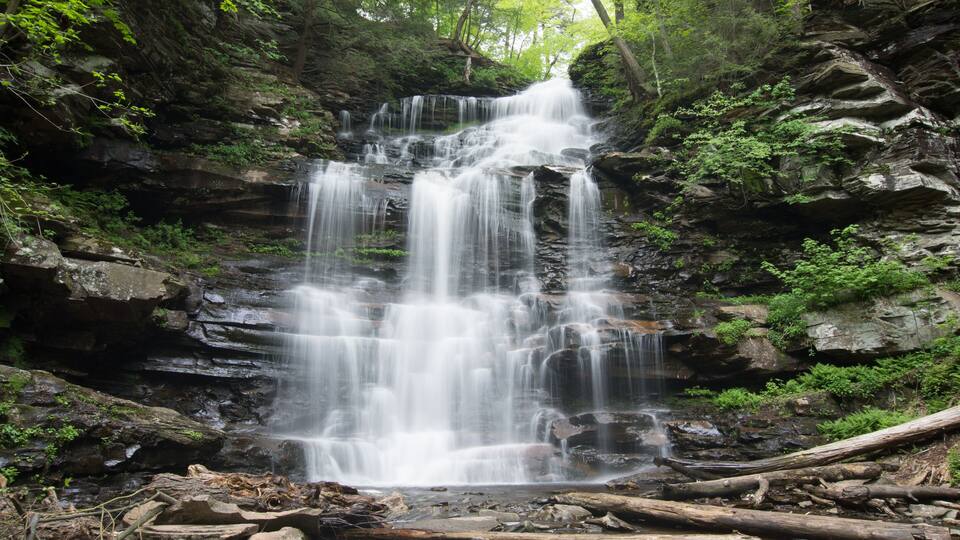A multi-tiered waterfall surrounded by dense forest.