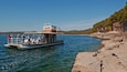 Un bateau avec des personnes à bord, au bord d’une côte rocheuse.