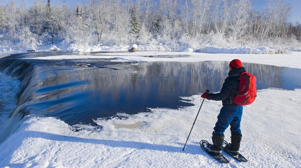Snowshoeing in winter along Whiteshell River at Rainbow Falls, Whiteshell Provincial Park; Manitoba, Canada