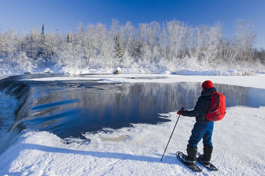 Snowshoeing in winter along Whiteshell River at Rainbow Falls, Whiteshell Provincial Park; Manitoba, Canada