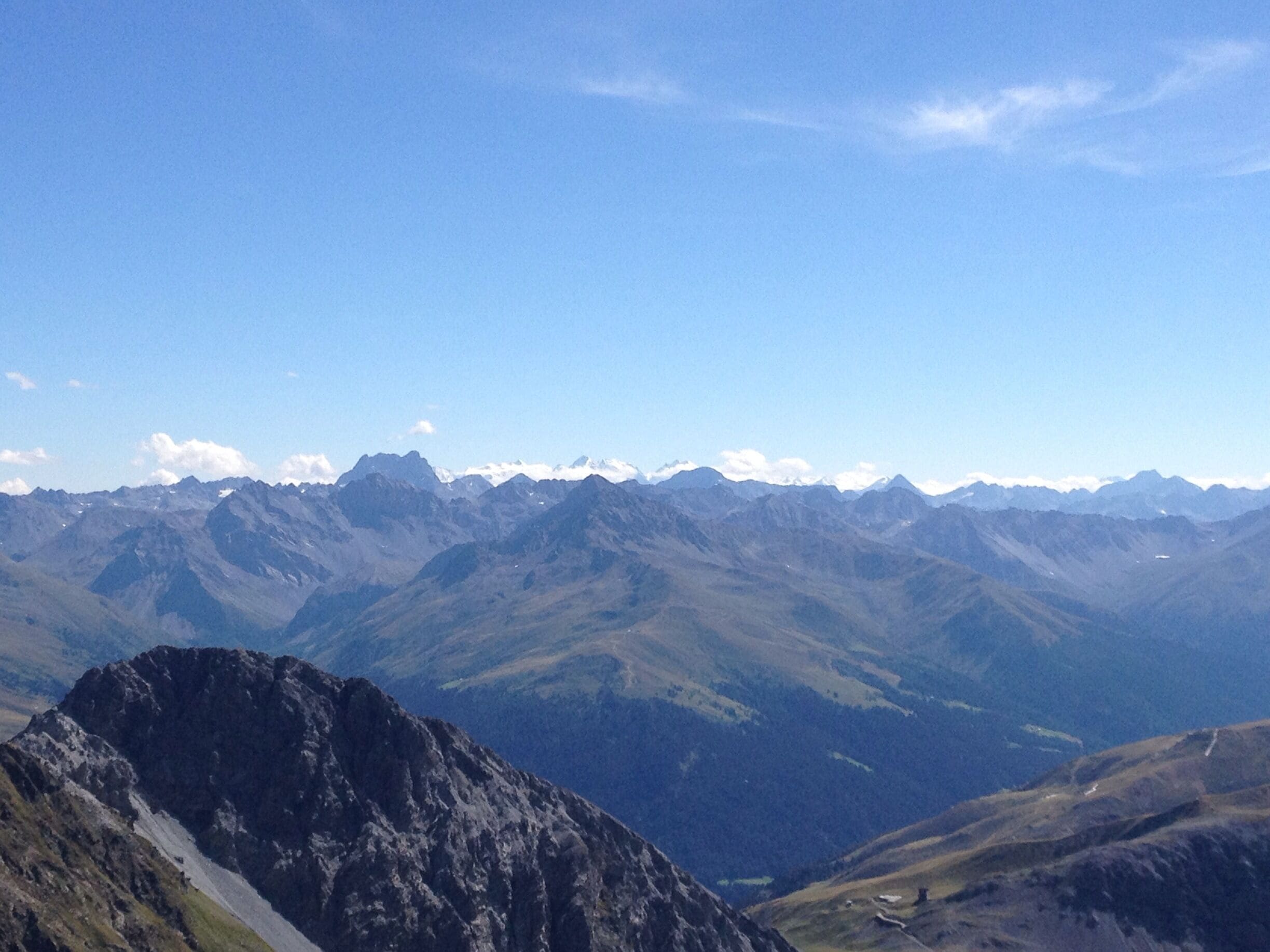 A mountain range with a prominent rocky peak in the foreground and a valley below.