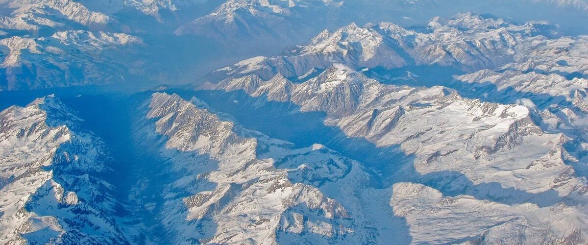 A snow-covered mountain range with a deep valley and a lake.