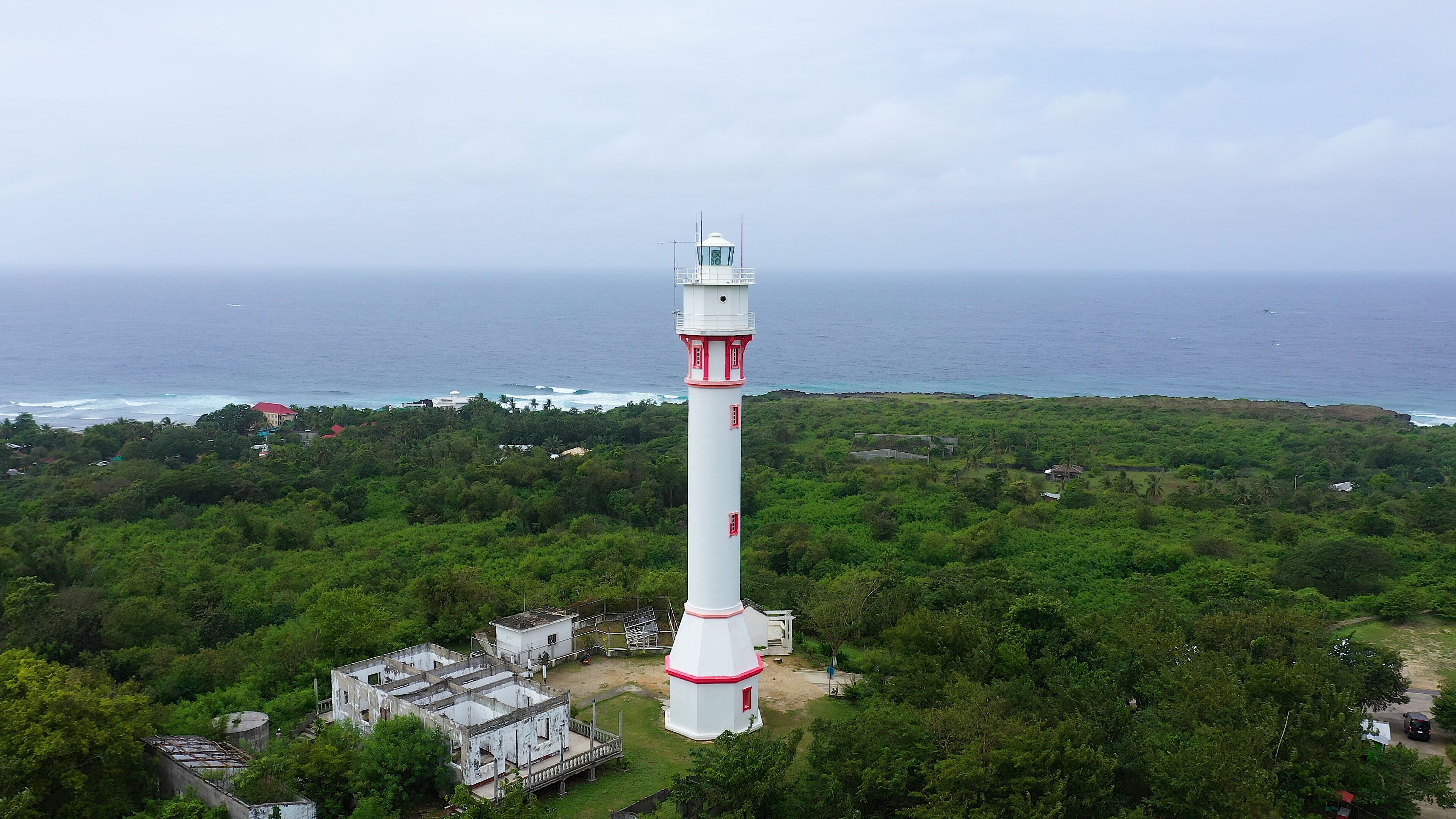 Lighthouse on a hill near the sea. Ocean coast with rainforest and lighthouse. Lighthouse on a tropical island, top view. Cape Bolinao Lighthouse, Luzon, Philippines. Summer and travel vacation