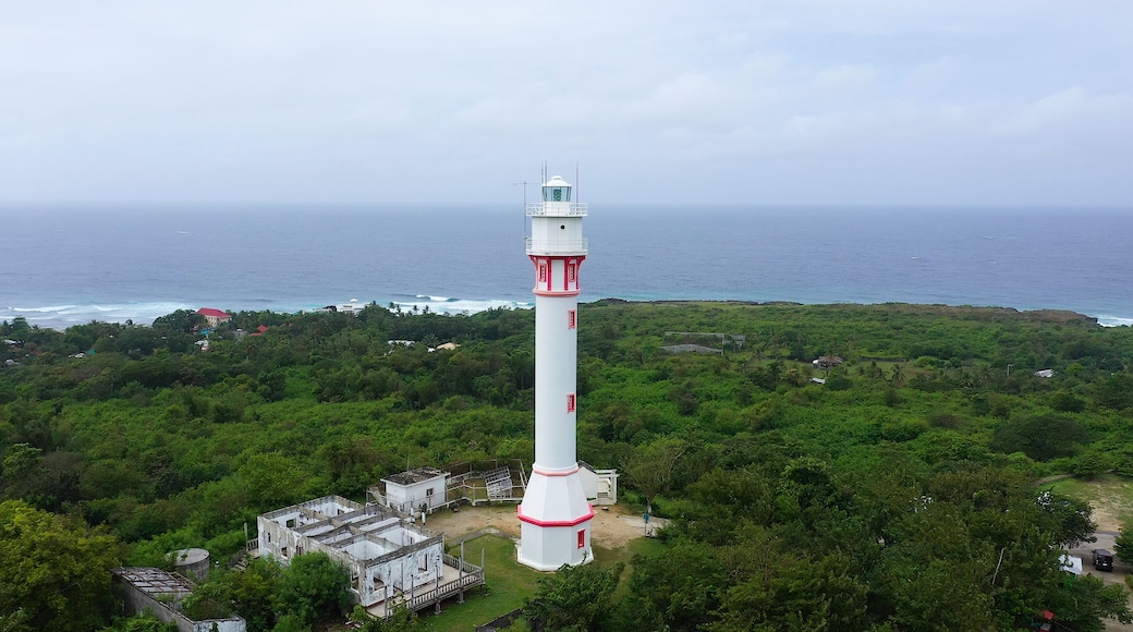 Lighthouse on a hill near the sea. Ocean coast with rainforest and lighthouse. Lighthouse on a tropical island, top view. Cape Bolinao Lighthouse, Luzon, Philippines. Summer and travel vacation