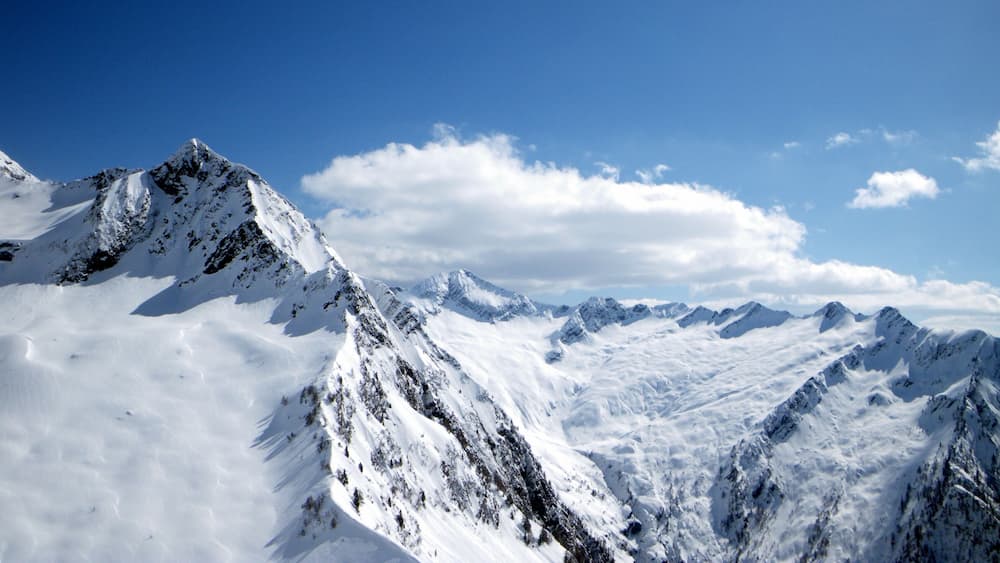A snow-covered mountain range with sharp peaks and a clear blue sky.