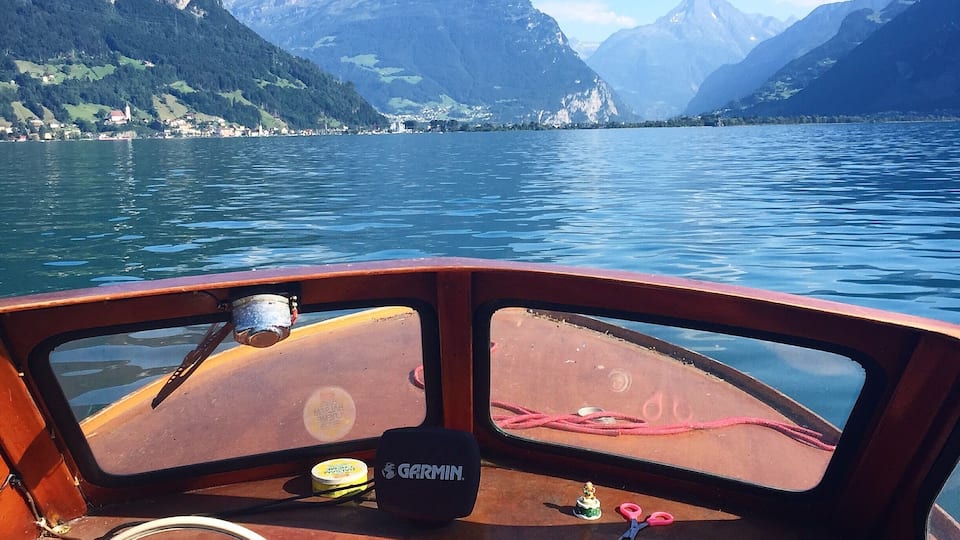 A boat's interior with a view of a lake and mountains.
