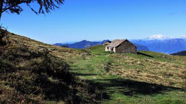 Die Alpe Cadinello (1828 m.ü.M.) am Südeingang des Tunnels von Mesolcina oberhalb von Roveredo im Grenzbereich zwischen den Schweizer Kantonen Tessin und Graubünden. In der Ferne steht der mächtige Monte Rosa.