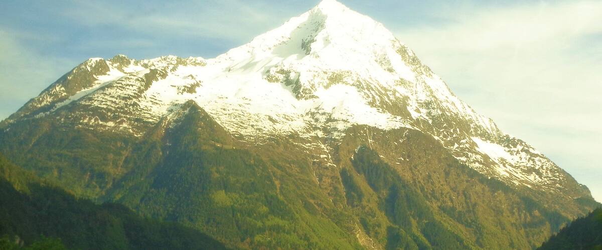 A snow-capped mountain with a valley and houses at its base.