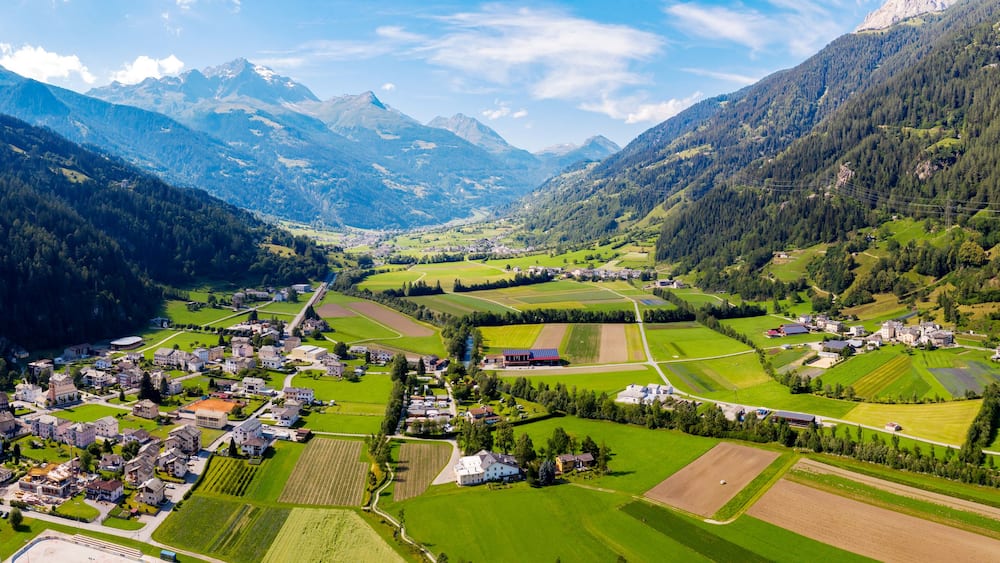 Une vallée où se trouve une petite ville, entourée de montagnes et de champs.