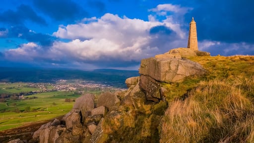 A stone monument on a hilltop with a view of a valley and a town below.
