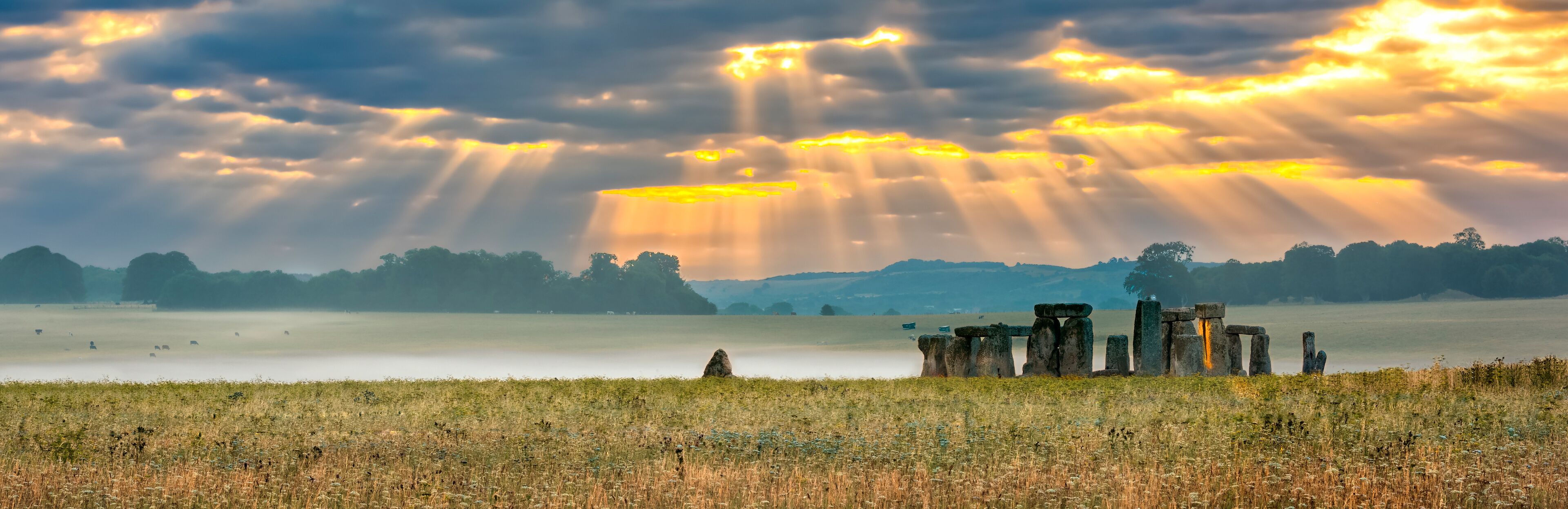 Amesbury, Wiltshire, United Kingdom - August 14, 2016: Cloudy sunrise over Stonehenge - prehistoric megalith monument arranged in circle.