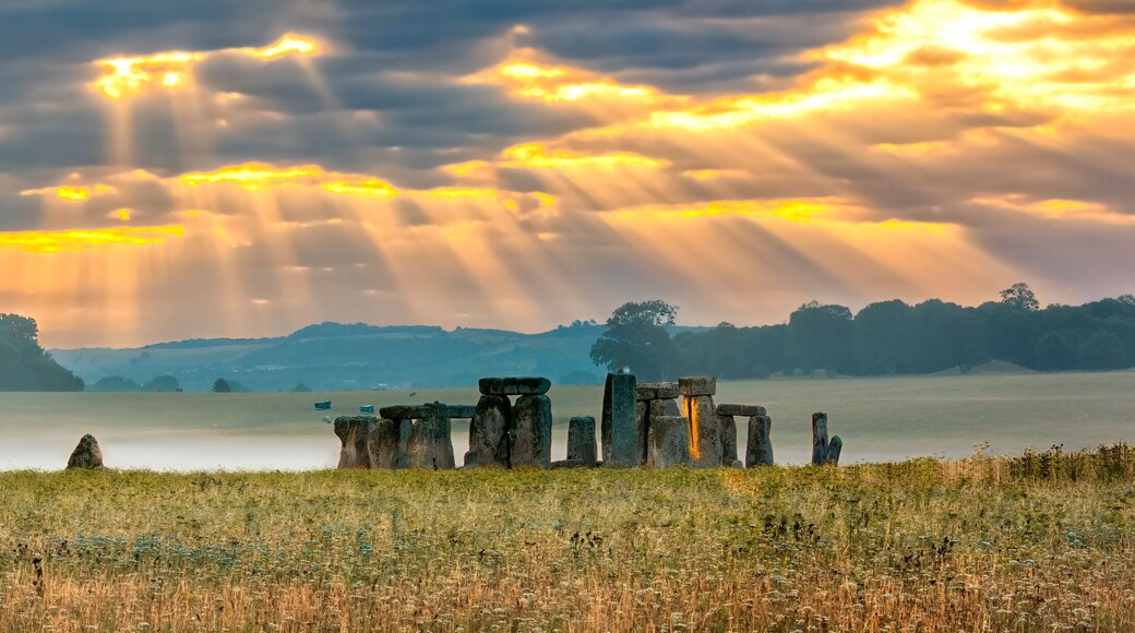 Amesbury, Wiltshire, United Kingdom - August 14, 2016: Cloudy sunrise over Stonehenge - prehistoric megalith monument arranged in circle.
